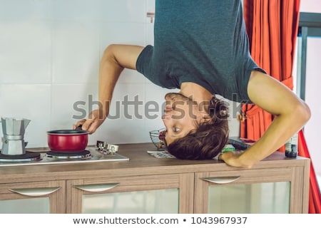 Foto d'archivio: A Man Stands On His Hands Upside Down In The Kitchen