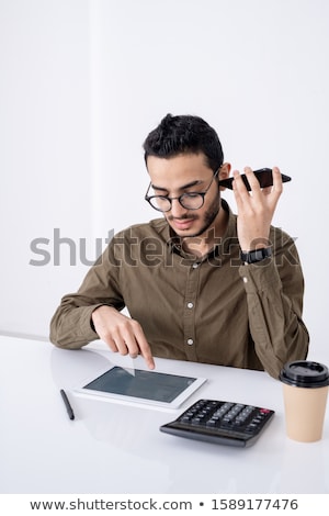 Zdjęcia stock: Busy Young Male Accountant With Smartphone By Ear Pointing At Touchpad Display