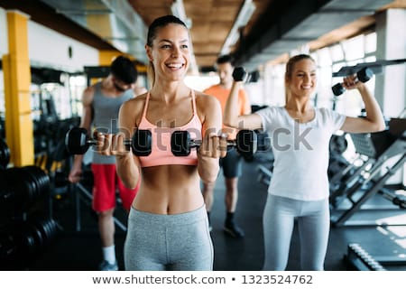Stok fotoğraf: Man And Woman Lifting Dumbbell In Gym