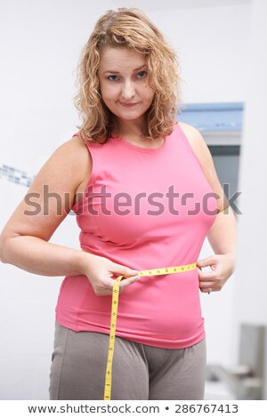 Stok fotoğraf: Frustrated Overweight Woman Measuring Waist In Bathroom