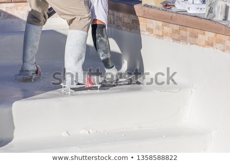 Stok fotoğraf: Worker Wearing Spiked Shoes Smoothing Wet Pool Plaster With Trow