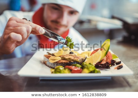 Foto stock: Proud Chef Garnishing An Almost Finished Dish In The Restaurant With Leave