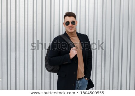 Foto d'archivio: Positive Joyful Young Male In Coat And Jeans With Backpack