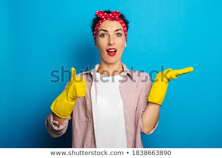 Stock photo: Cheerful Housewife In Blue Apron Holding Yellow Rubber Gloves