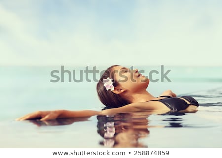 Foto d'archivio: Bikini Woman Lying Relaxing In Infinity Pool