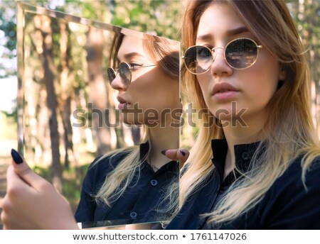 Foto stock: Blonde Girl Looking In Mirror With Forest Background
