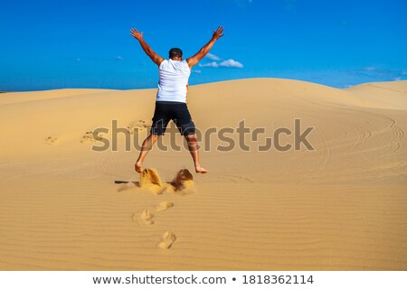 Stock foto: Beautiful Young Man Jumping Barefoot On Sand In Desert Enjoying Nature And The Sun Fun Joy And Fre