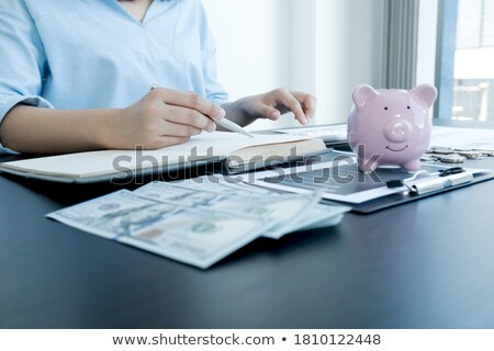 Foto stock: Businessman Putting Coins Into Piggy Bank And Using Calculator T