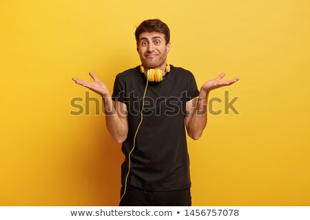 Stok fotoğraf: Photo Of Handsome Man With Uncertain Expression Spreads Hands Wears Glasses And Headgear Isolated