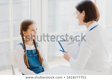 Stok fotoğraf: Back View Of Attentive Female Pediatrician Listens Carefully Child Complaints Writes Down Notes In