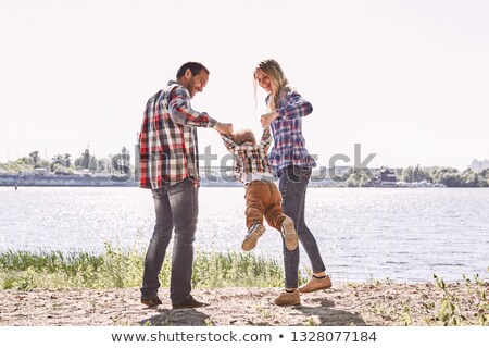 Stockfoto: Smiling Cute Woman In Checkered Shirt Standing And Holding Sunglasses