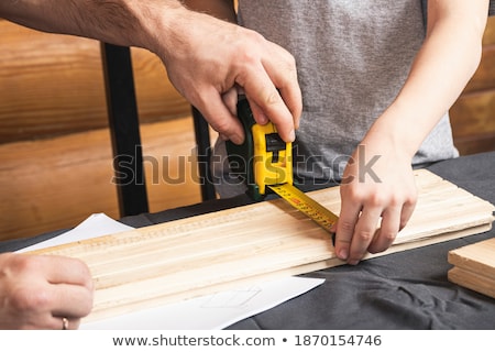 [[stock_photo]]: Dad And Son With Ruler Measuring Plank At Workshop