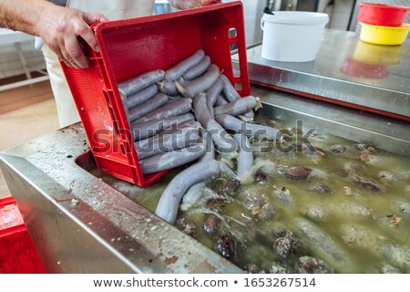 Zdjęcia stock: Butcher Emptying Container Of Sausages Into Cooking Water