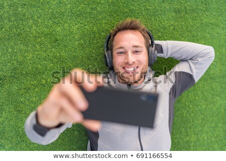 Happy Man Watching Phone Video App Listening With Headphones And Smartphone Relaxing Outside On Summ Stockfoto © Maridav