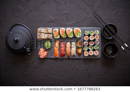 Foto stock: Assortment Of Different Kinds Of Sushi Rolls Placed On Black Stone Board