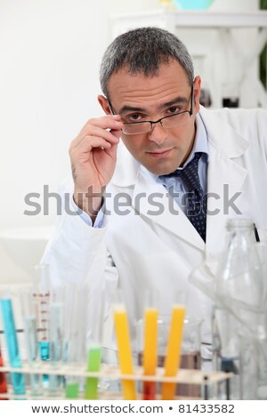 Foto stock: Scientist Touching His Glasses Behind Test Tubes In A Laboratory