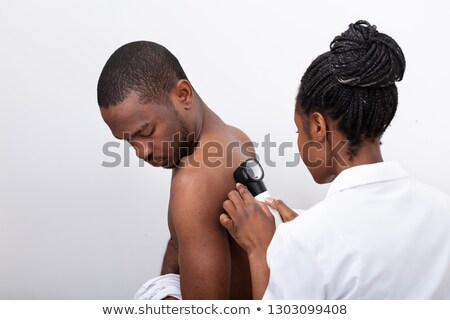 Stockfoto: Female Doctor Examining Skin Of Male Patient