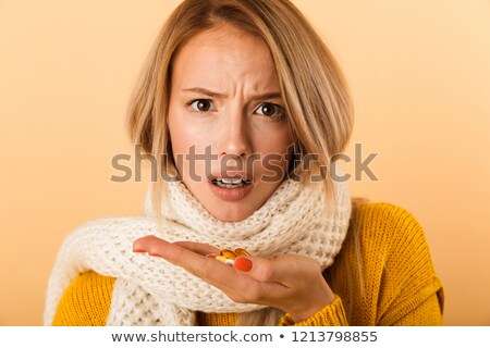 Foto d'archivio: Beautiful Sad Ill Young Woman Isolated Over Yellow Background Wearing Scarf Holding Pills