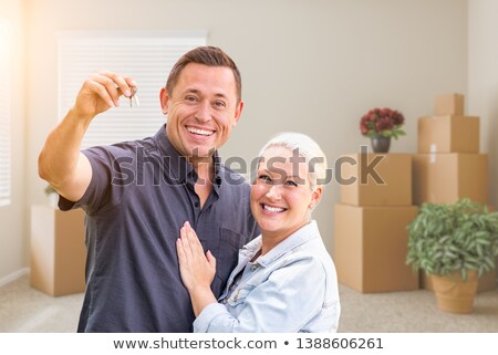 Foto stock: Happy Couple With New House Keys Inside Empty Room With Boxes