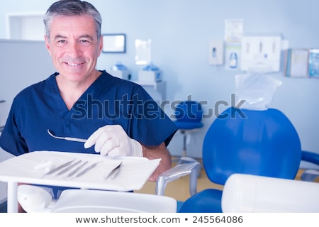 Stock photo: Dentist In Blue Scrubs Holding Dental Tools