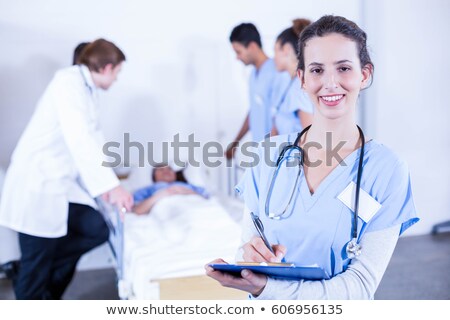 [[stock_photo]]: Portrait Of Smiling Young Male Doctor Writing On A Patients Med