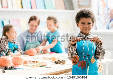 Stock fotó: African Schoolboy In Blue Apron Holding Stick With Halloween Decorations