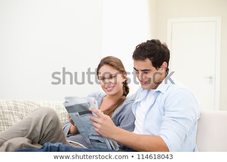 Foto stock: Couple Reading Newspaper On Couch