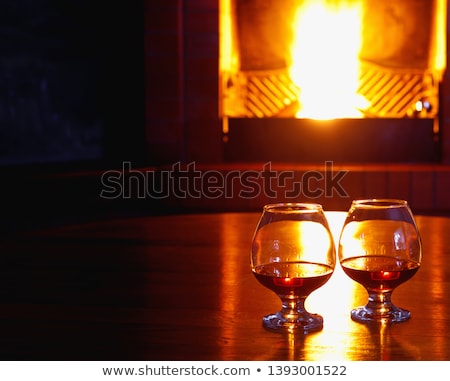 Foto stock: Two Tanks Of Cognac On The Old Brick Fireplace With A Bright Fir