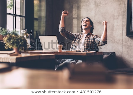 Stock fotó: Businessman Sitting With Arms Raised At Desk