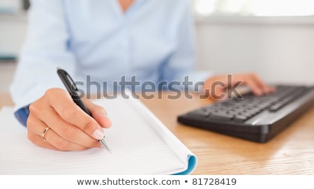 Stock photo: Gorgeous Brunette Businesswoman Typing And Writing In Her Office