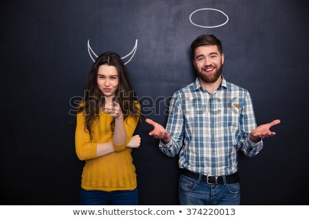 Сток-фото: Beautiful Couple Standing Over Blackboard With Drawn Hornes And Halo