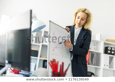 Stok fotoğraf: A Young Girl Stands Near A Table In The Office And Explains The Schedule On The Magnetic Board