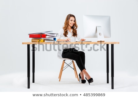 Stock foto: A Beautiful Young Girl Is Sitting At An Office Desk Holding A Pen Near Her Face And Reaching For Bri