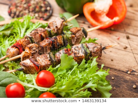 Сток-фото: Grilled Pork And Chicken Kebab With Paprika In Round Wooden Plate Of Lettuce Salad On Wooden Backgr