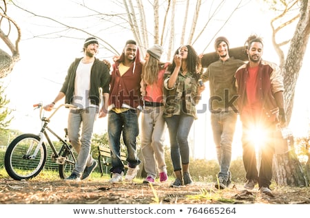 Foto d'archivio: Multiracial Young People Walking In The Autumn Park And Having F