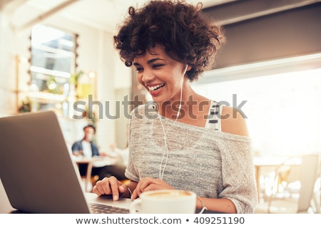 ストックフォト: Smiling Woman Sitting By Table In Cafe And Using Laptop