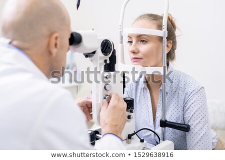 Foto stock: Young Female Looking At Ophthalmologist While Having Her Eyesight Examined