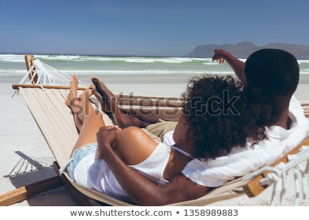 Stock photo: Front View Of Young Multi Ethnic Couple Relaxing On Hammock At Beach On Sunny Day They Seem Happy