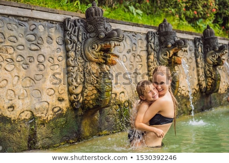 Stock photo: Mom And Son Travelers In Hot Springs Banjar Thermal Water Is Released From The Mouth Of Statues At