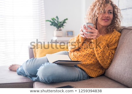 ストックフォト: A Beautiful Adult Woman With Curly Hair In A Sweater On The Background Of The Garden With Cherry Blo