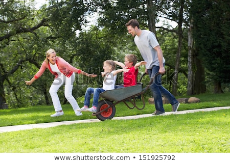 ストックフォト: Parents Giving Children Ride In Wheelbarrow