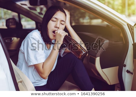 Foto stock: Female Driving Car Holding Alcoholic Bottle