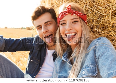 Stockfoto: Happy Young Couple Sitting Together On A Haystack