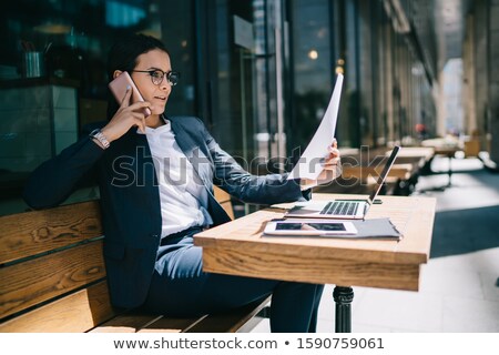 Foto stock: Businesswoman During Mobile Phone Conversation Looking At Laptop