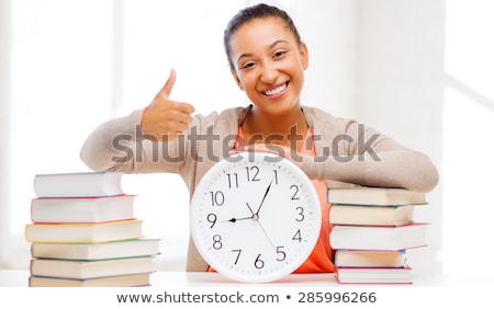 Foto stock: Student With Books And Clock Showing Thumbs Up