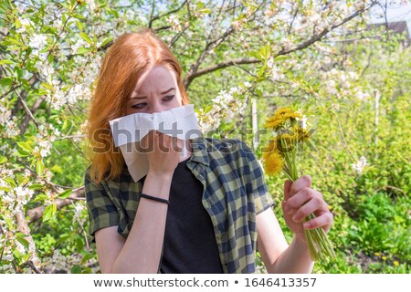 ストックフォト: Young Woman Sneezes In The Park Against The Background Of A Flowering Tree Allergy To Pollen Concep