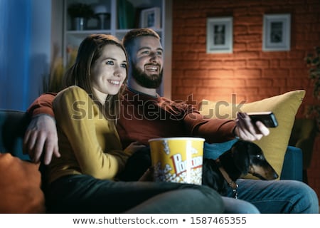 Stockfoto: Couple Watching Television With Their Pet Dog In Living Room At Home