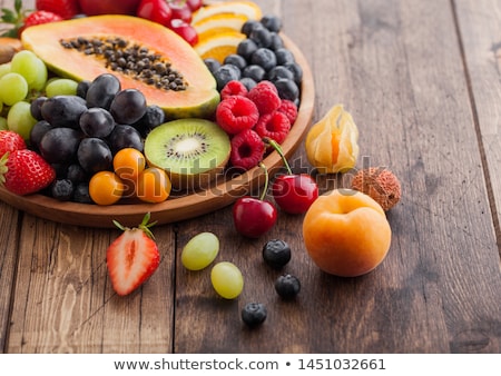 Stockfoto: Fresh Raw Organic Summer Berries And Exotic Fruits In Round Wooden Plate On Wooden Kitchen Backgroun