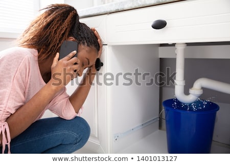 Stock photo: Woman Calling Plumber In Front Of Leaking From Sink Pipe