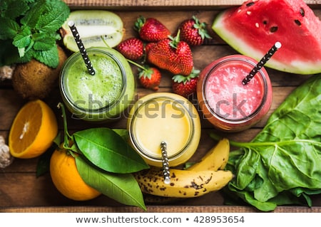 Foto d'archivio: Freshly Blended Red Strawberry Fruit Smoothie In Glass Jars With Straw Mint Leaf Cut Ripe Berry T